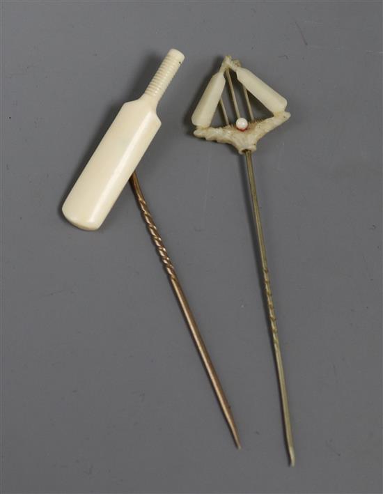 Two ivory mounted cricket related stick pins, one modelled as a cricket bat, the other as cricket bats, ball and stumps.